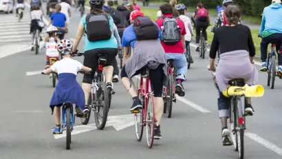 Large group of people and children on bikes in street.