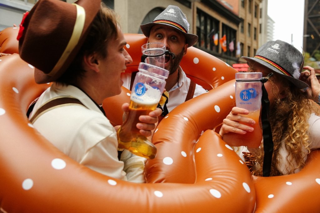 People drinking beer and holding large inflatable pretzels at Oktoberfest festival in San Francisco, California.