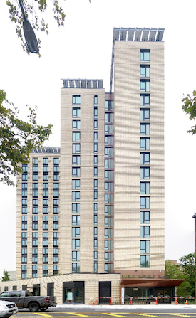 A high-rise apartment building rises above a parking lot.