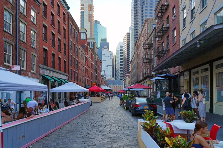 A New York STreet is filled with people and dining spaces where cars used to park, during the Covid-19 pandemic.