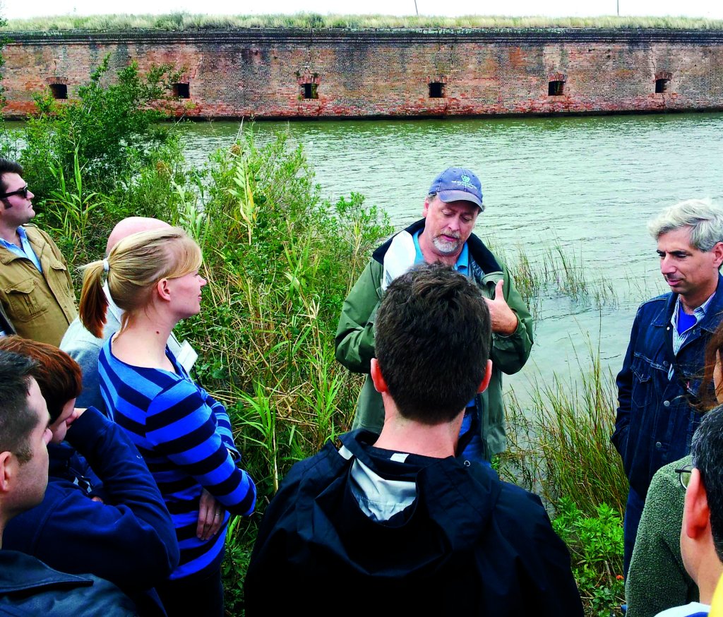 Image of people speaking to each other outside next to a body of water