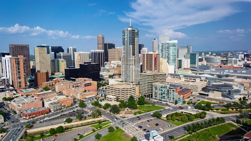 Image of cityscape with a clear but slightly cloudy sky and tall skyscrapers, roads, and parks