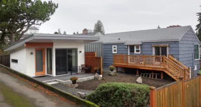 White accessory dwelling unit in backyard of small grey home in Seattle, Washington.