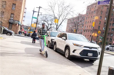 Person riding electric scooter on New York City sidewalk.
