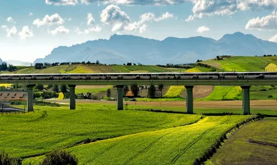 AI-generated image of high-speed rail trail in elevated track in green hilly farmland.