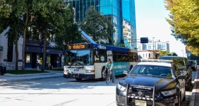 Public transit bus on street with cyclist riding next to it in Madison, Wisconsin.