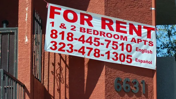 For Rent sign on red stucco apartment building.