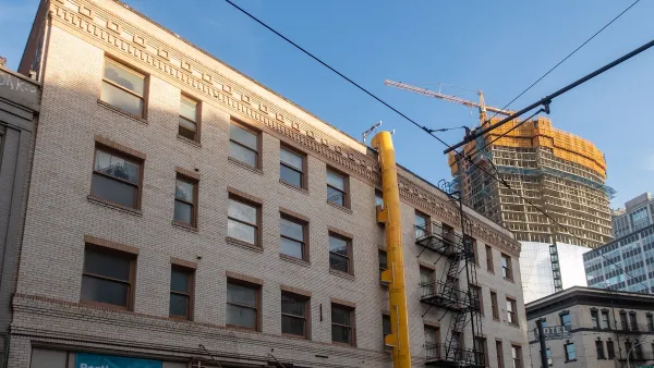 Brick building with high-rise under construction with yellow crane in background in downtown Portland, Oregon.