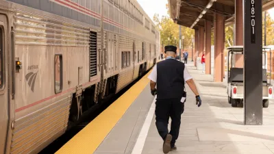Conductor walks down platform next to Amtrak train at station in San Jose, California.