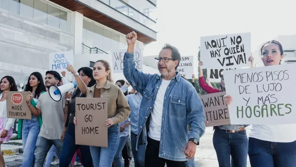 Group of anti-gentrification protesters holding signs like "Tourist go home" in Mexico City.