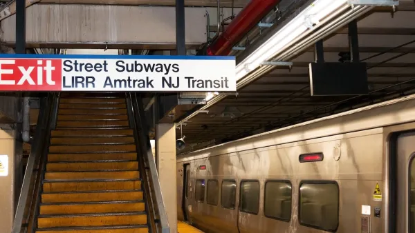 "Street Subway - LIRR - Amtrak - NJ Transit" with Exit sign in front of stairway on subway platform at Penn Station with silver train stopped at right.