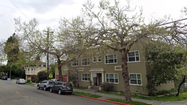 Two-story green apartment building in residential neighborhood in Berkeley, California with tall street trees.